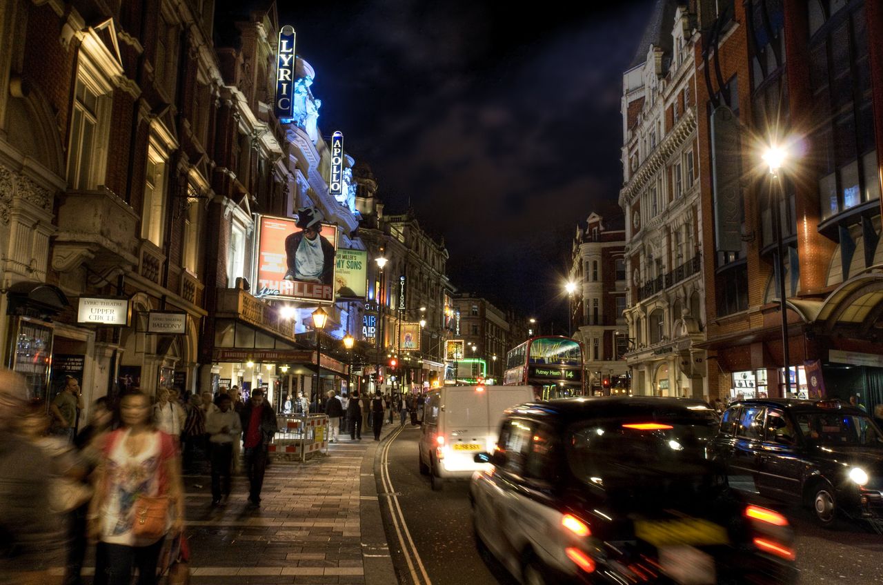 Shaftesbury Avenue de nuit, enseignes lumineuses du Lyric et de l'Apollo, taxis noirs et bus à impériale dans la rue